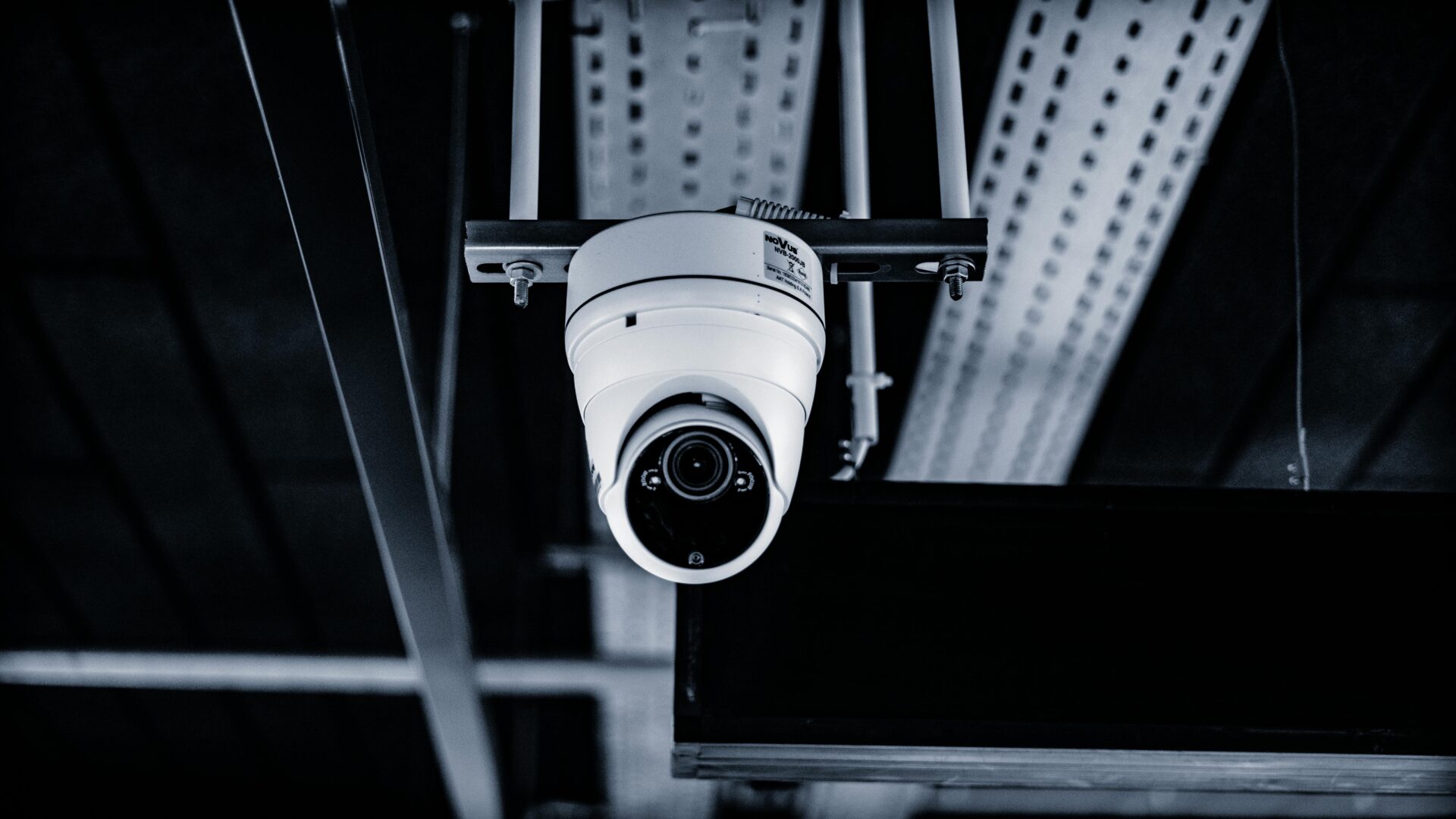 A camera hanging from the ceiling of an industrial building.